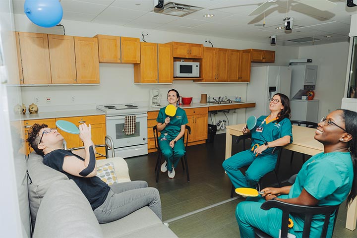 An actor plays a simulated patient named Alex Bledsoe who has multiple sclerosis while occupational therapy students, Georgia Ray, left, of Olive Branch, Mississippi; Emily Morse, of Cordova; and Akosua Odei, of Nashville, play a game with her.