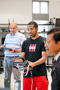 Erkan Kaplanoglu, interim department head and director of Biomechatronic and Assistive Technology Lab, and Cam Jones, a Tuskegee University student attending the iCompBio2023-REU Summer Program at UTC, provide a demonstration for Cap Nguyen.