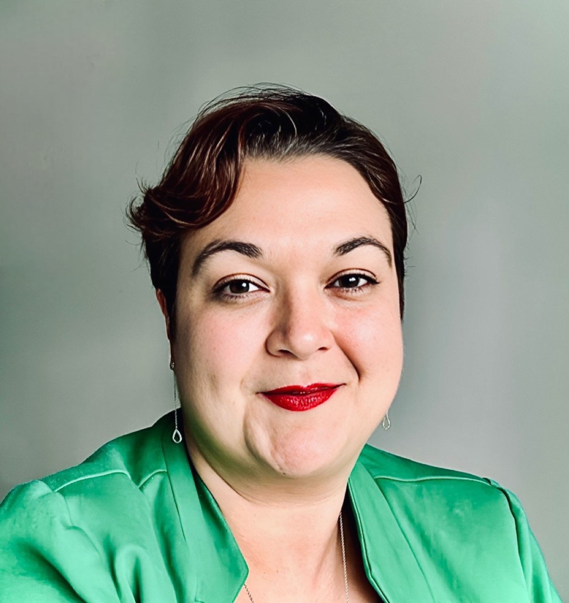 Headshot of a woman wearing a green top, with short brown hair.