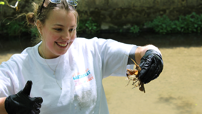 Female wearing gloves, holding a crawfish.