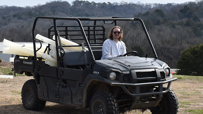 A white man, sitting in a four-wheeler, with mountains in the background.