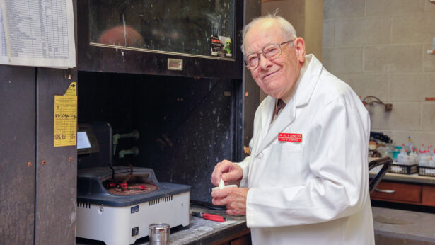 An old man wearing glasses and a white lab coat.