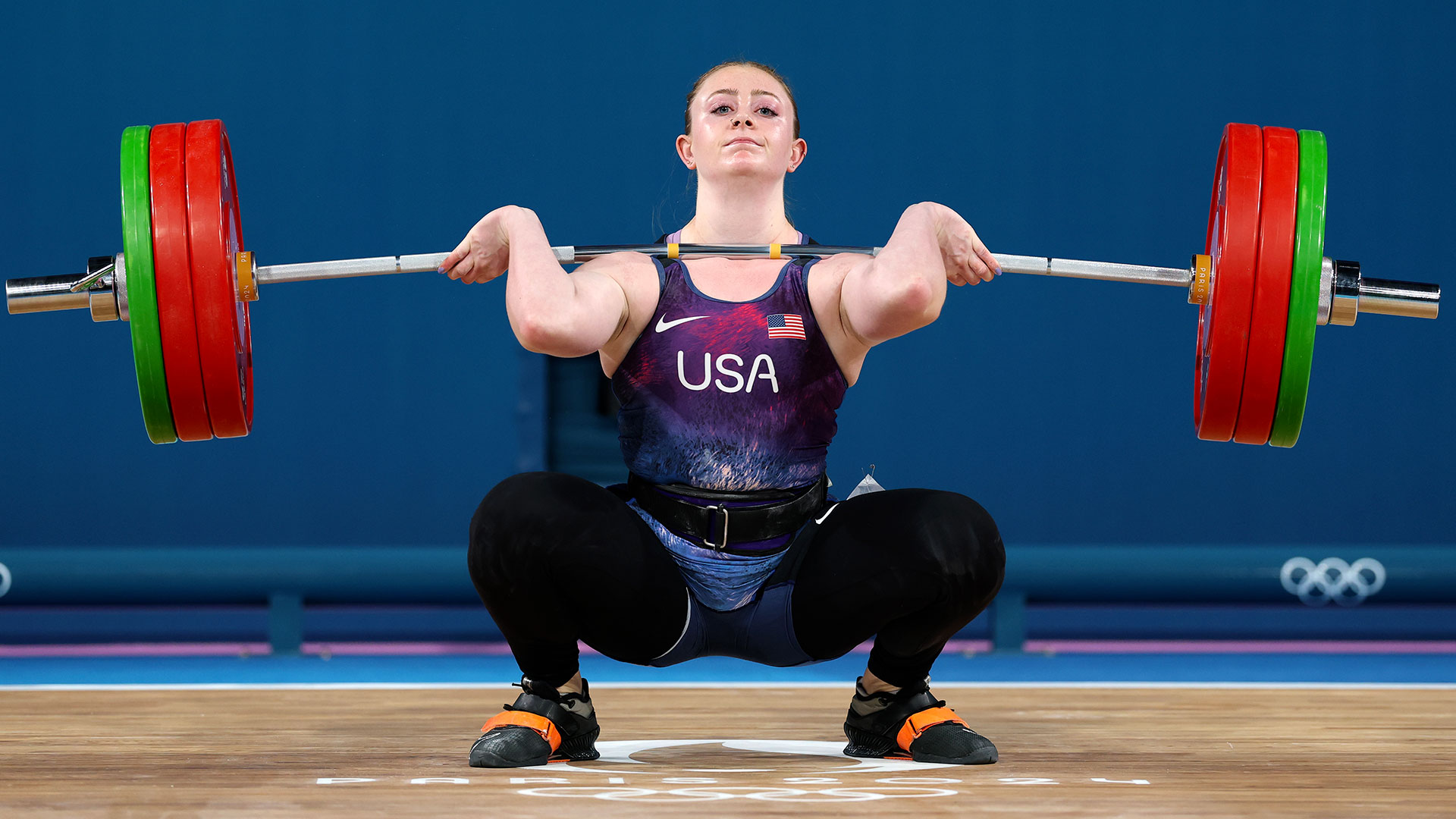 A young, white female clean lifting at the 2024 Olympics.