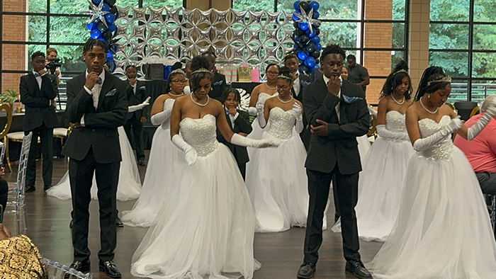 A group of black teenagers in formal attire dancing.