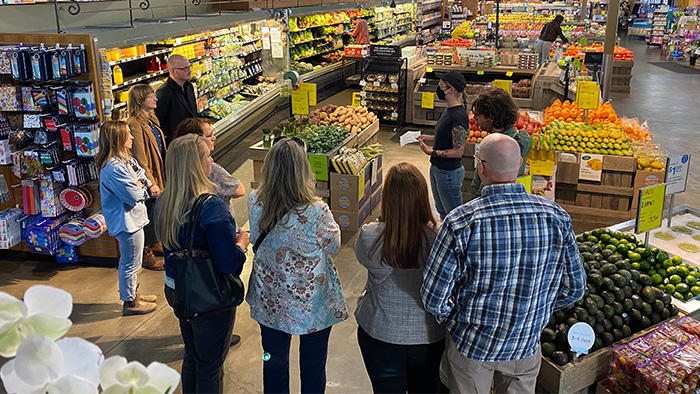 A group of people touring a local grocery store's produce section.