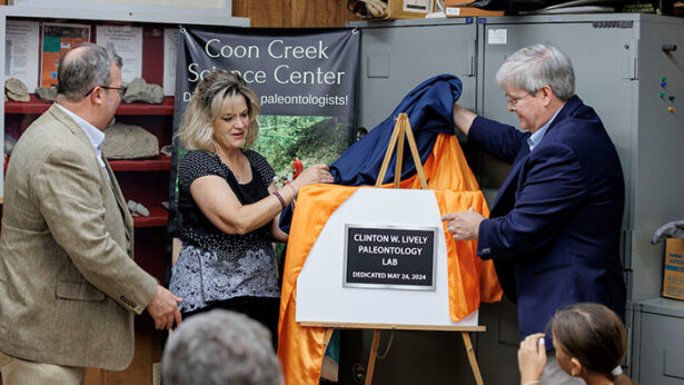 Two men and a women unveil a new building name.