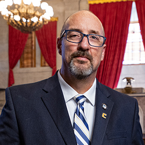 A white male in a business suit with a striped tie.