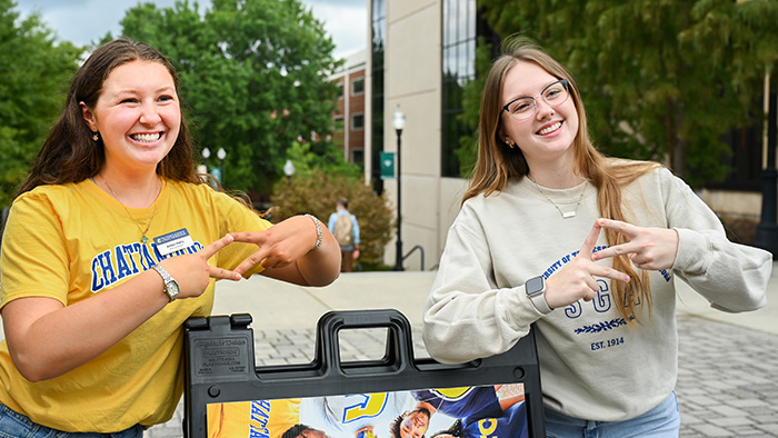 Two girls showing the UTC Mocs handsign.