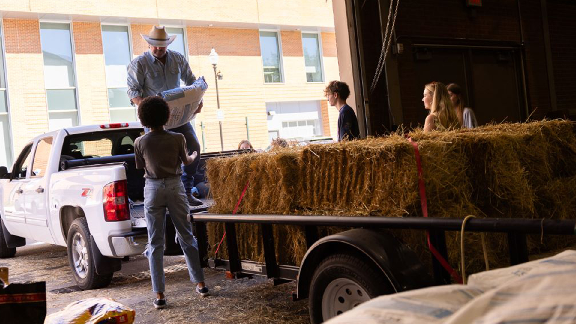 A group of men and women help load a pickup with supplies.