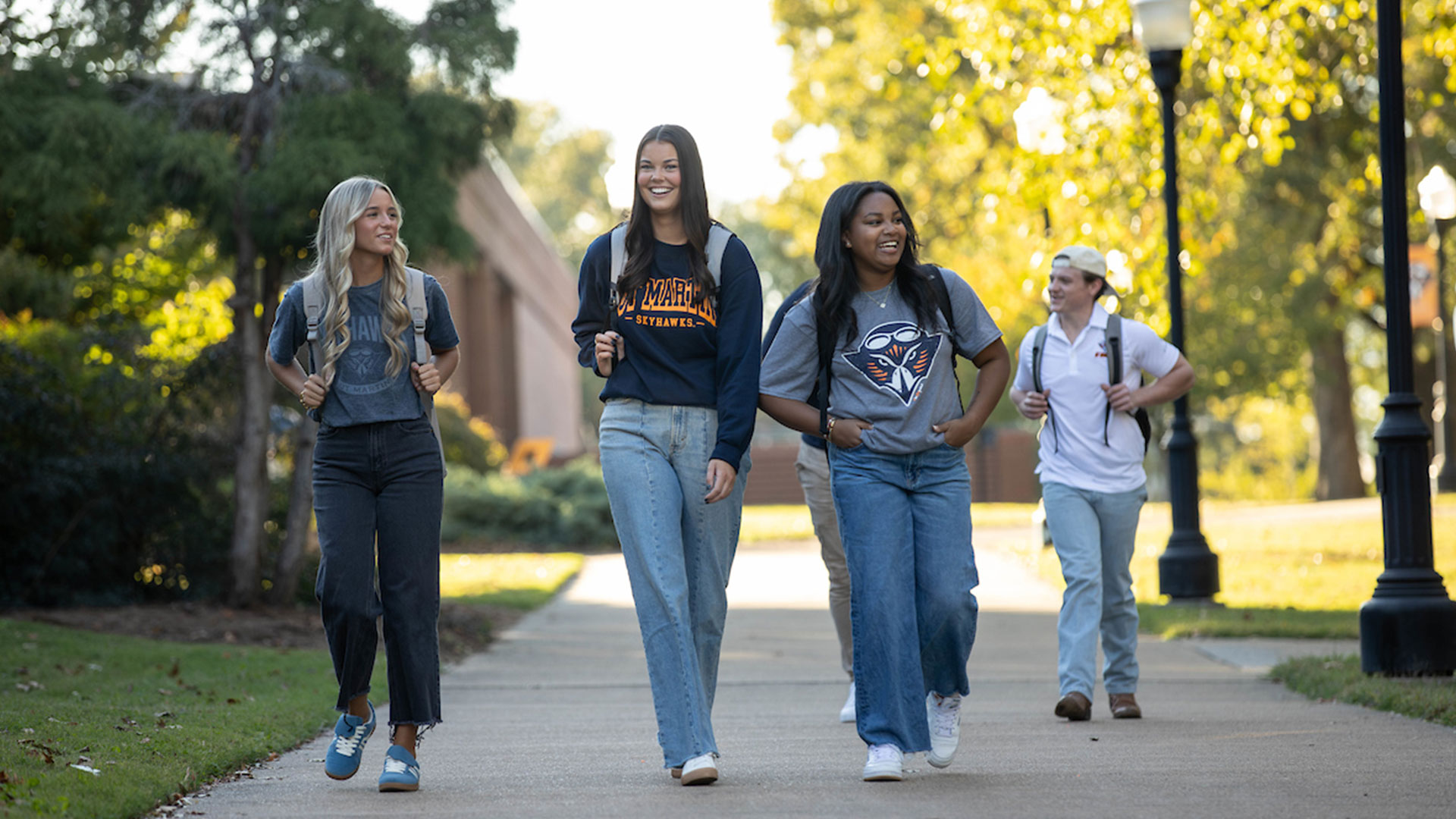 A group of students walking across a campus sidewalk.