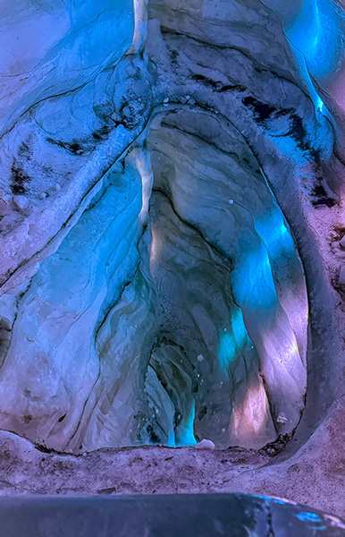 A deep ice cavern glowing with blue and purple lighting.