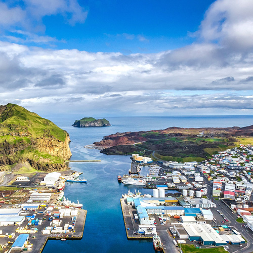 An aerial view showing the surrounding landscape and ocean channel leading into an island's port.