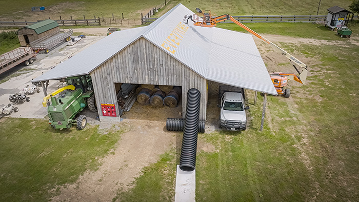 An artist uses a crane lift to paint on a barn roof.