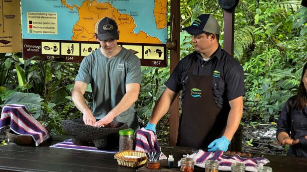 Three people conducting a demonstration on how to make chocolate from cacao beans.