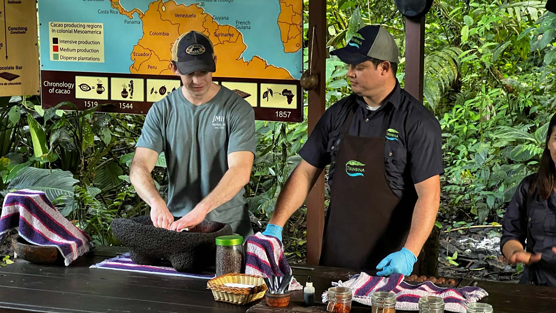 Three people conducting a demonstration on how to make chocolate from cacao beans.
