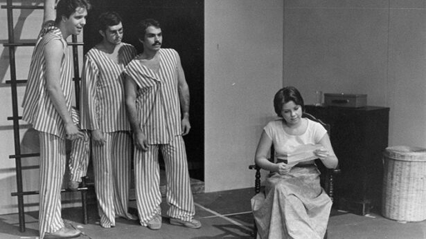 An old black and white photo of a group of actors participating in a theatre production.