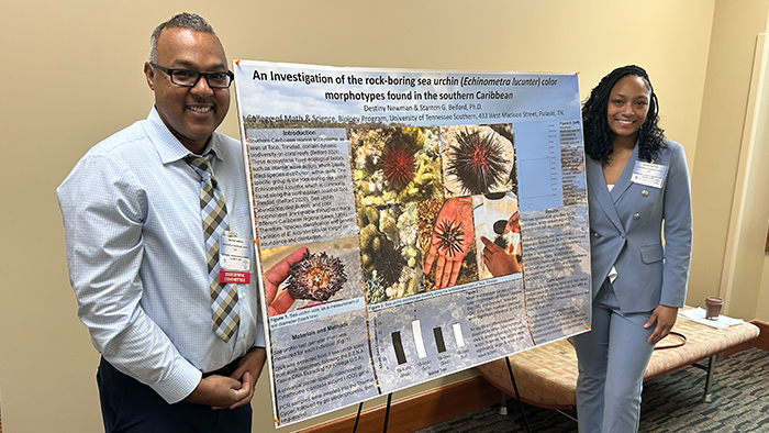 A female student and her mentor stand next to her research display on oceanic life.