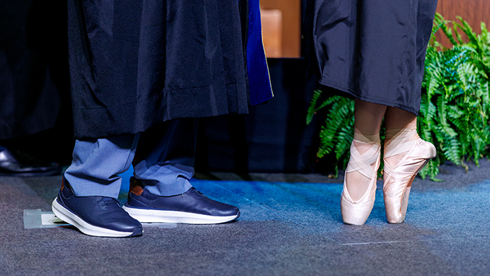 A close-up photo of a students feet as she walks en pointe across the graduation stage.