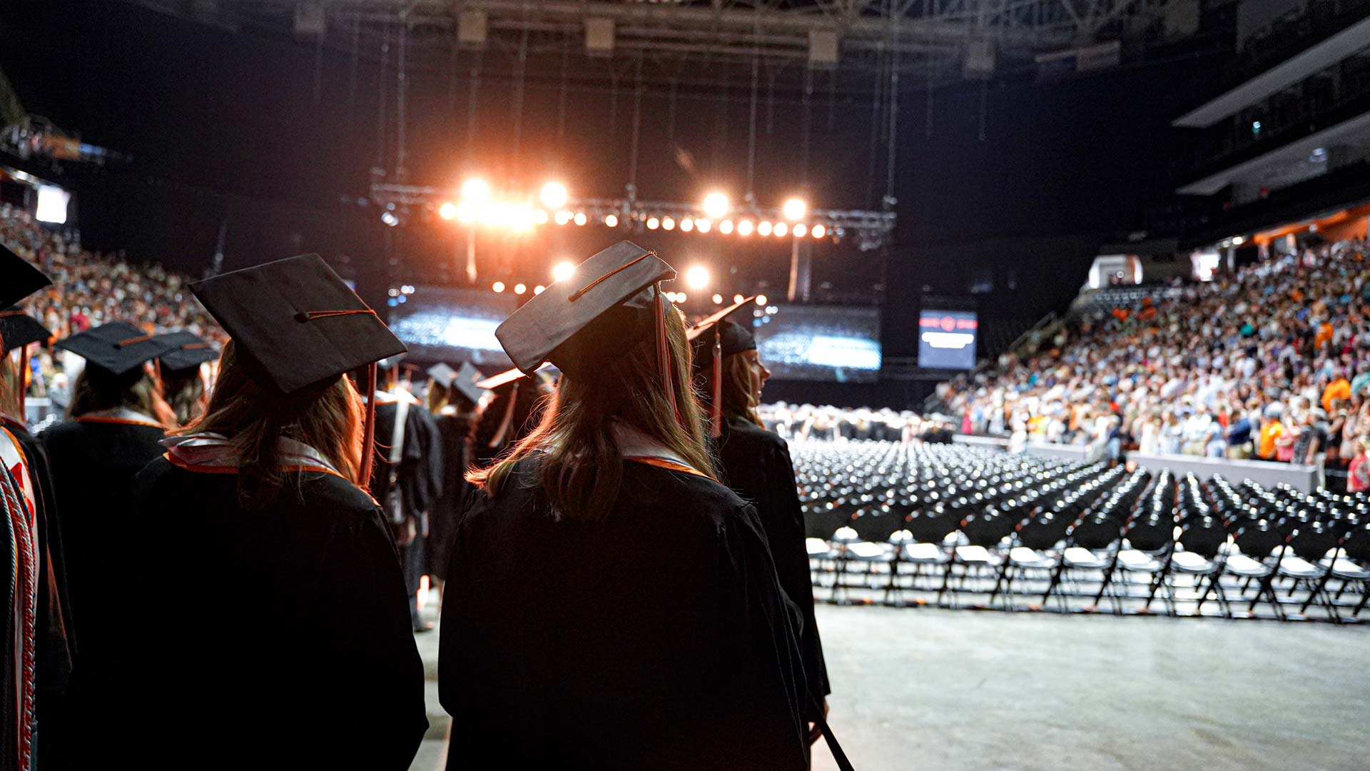 Students enter an arena in preparation for their college graduation ceremony.