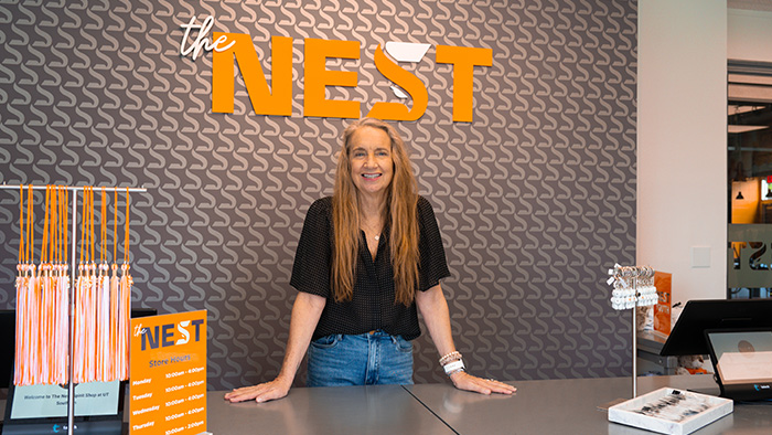A woman with long brown, graying hair, stands behind a counter inside the UT Southern campus store.