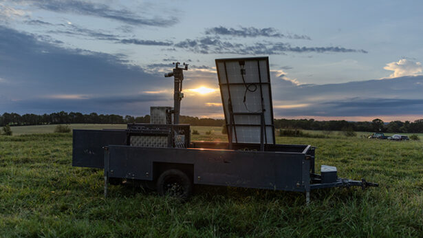 Sunset over a large farm field, with a large mechanical feeding station.
