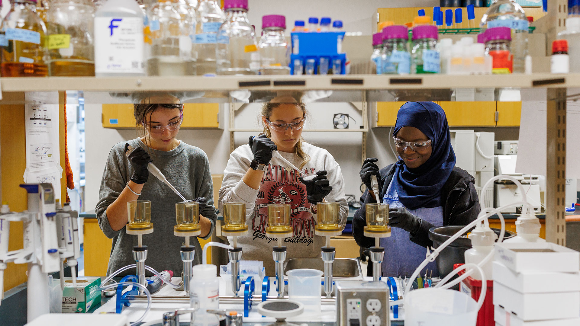 Three female students working side by side in a laboratory.