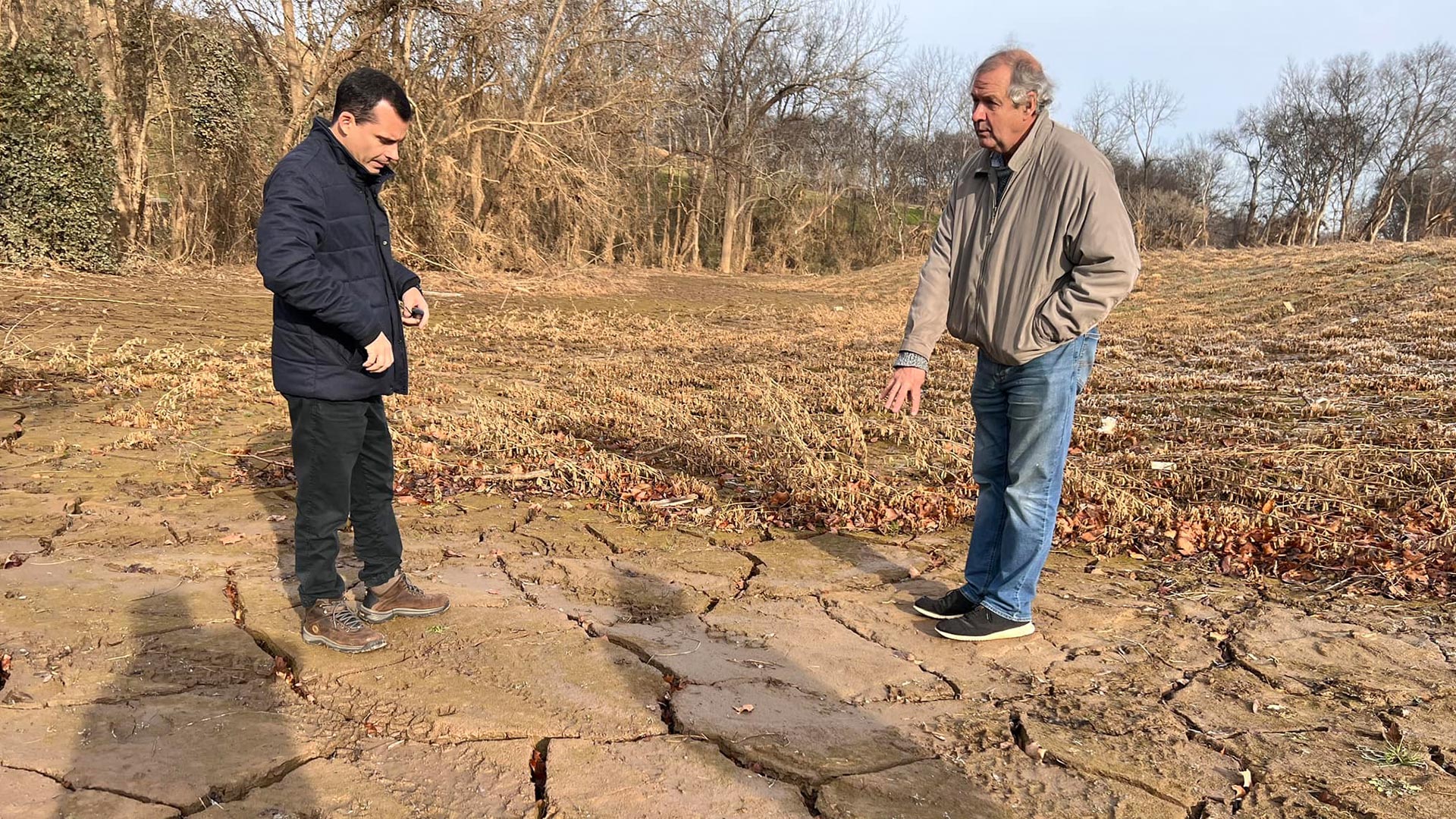 Two men standing in a muddy field.