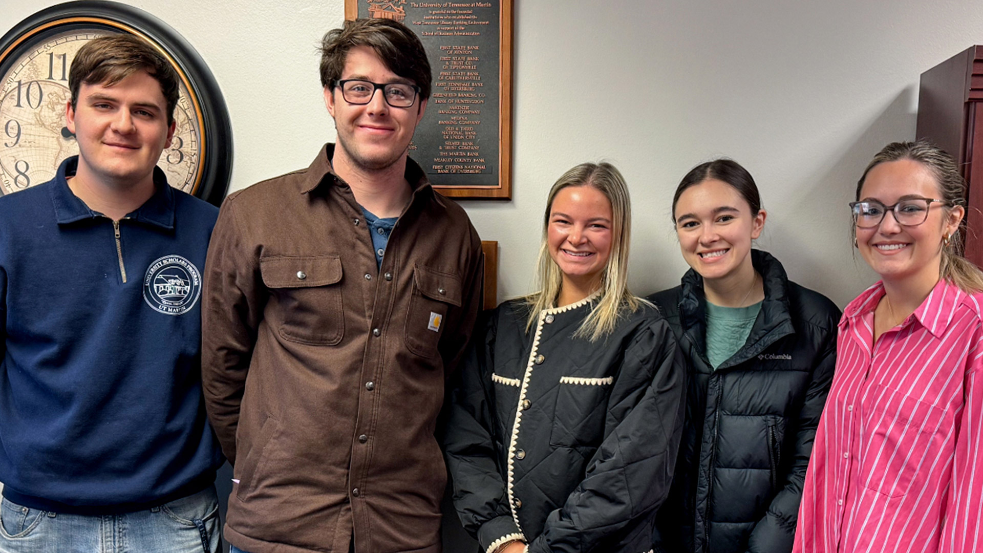 A group of students standing together for a photo inside an office.