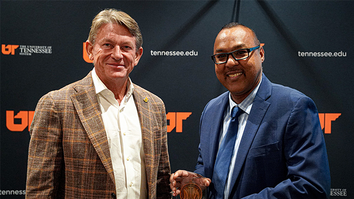 Two men pose for a photo during an awards ceremony.