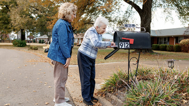 Two women collecting mail from a mailbox.
