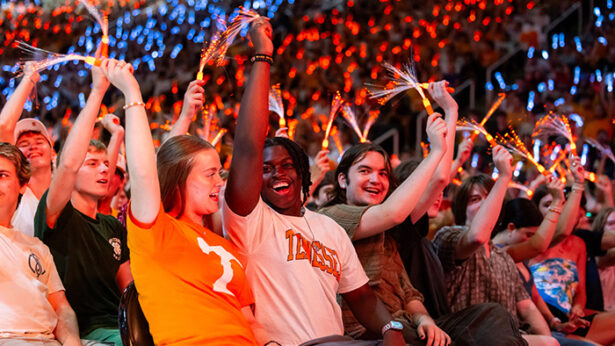 A crowd of students waving orange glow sticks.