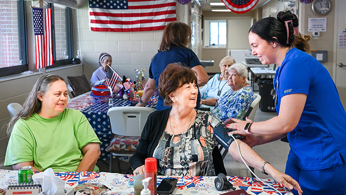 Two women treating a group of elderly patients.