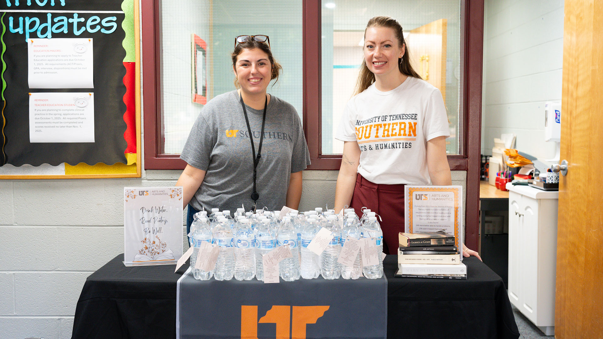 Two women standing behind a table laid out with water bottles.