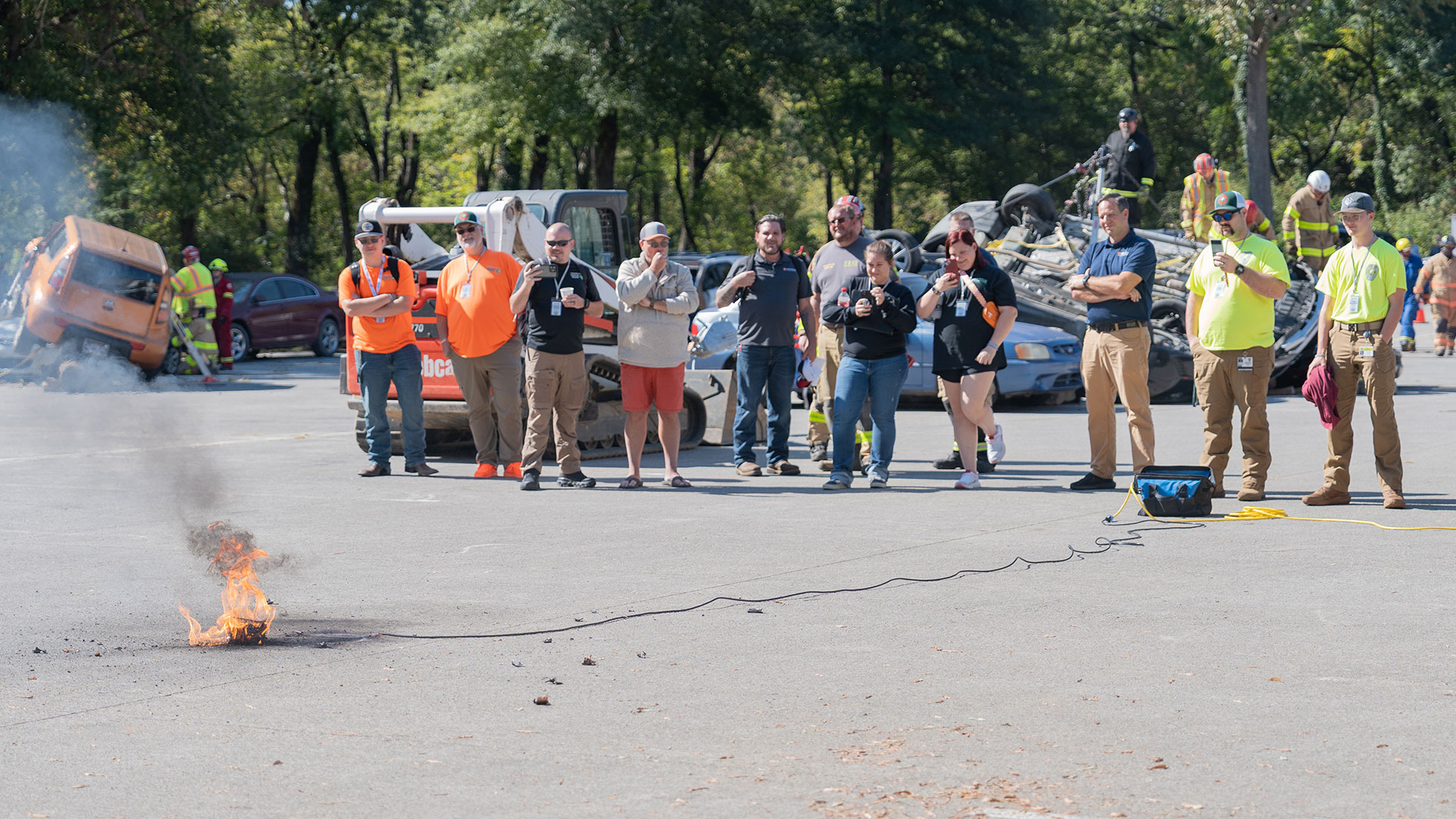 A group of people taking videos of a battery fire demonstration.