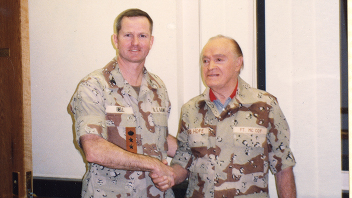 Two military personnel wearing desert fatigues shaking hands.