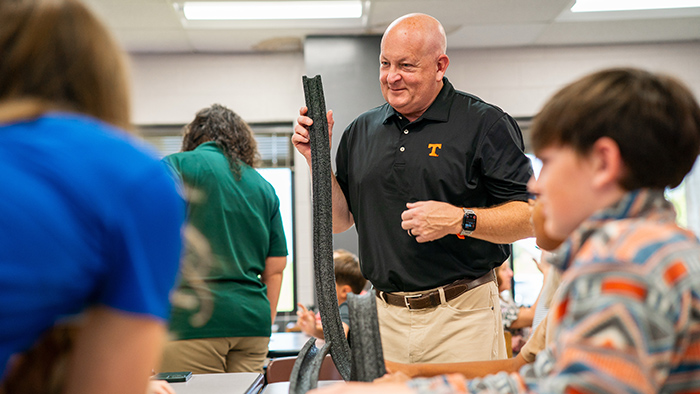 A man examines a piece of Styrofoam in a classroom.