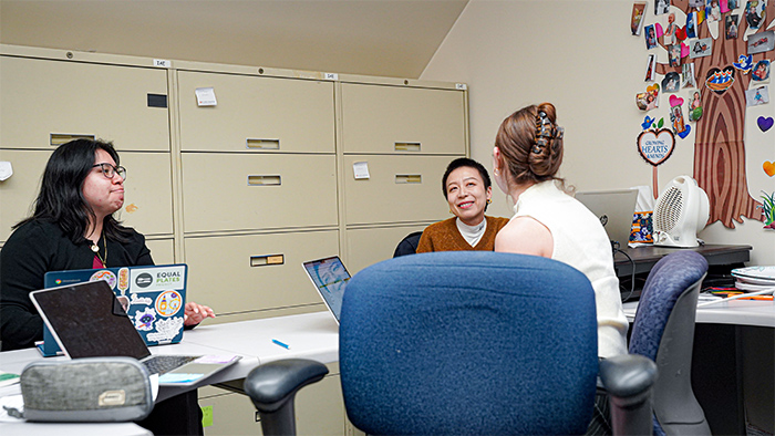 Three women sitting around a table while using their computers.