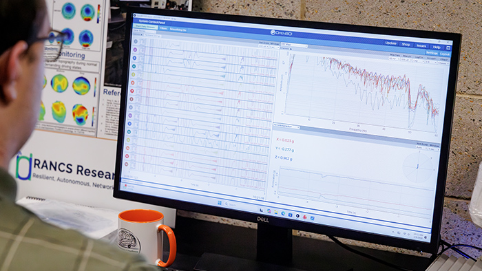 A person using a computer showing a readout of brain activity.