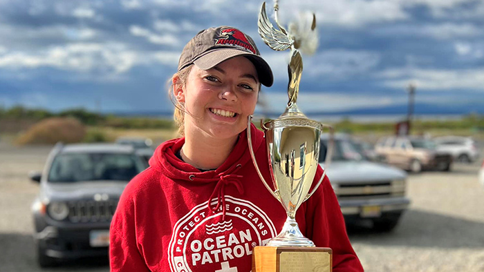 A girl holding a large trophy.