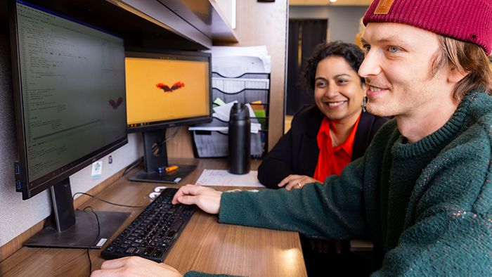 A woman and young man examining data on some computer screens.