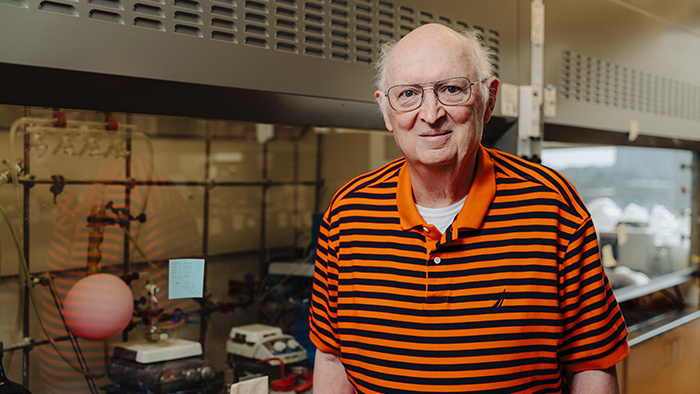 A man wearing a striped orange and black shirt, in a science lab.
