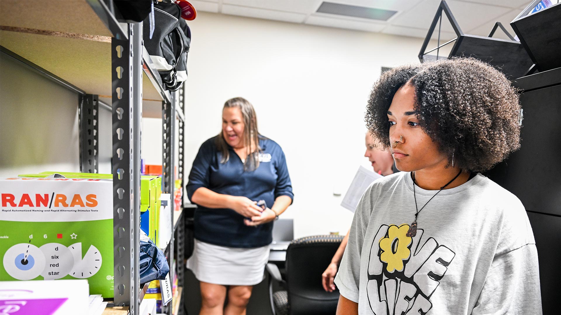 A group of people looking at supplies on a set of shelves.