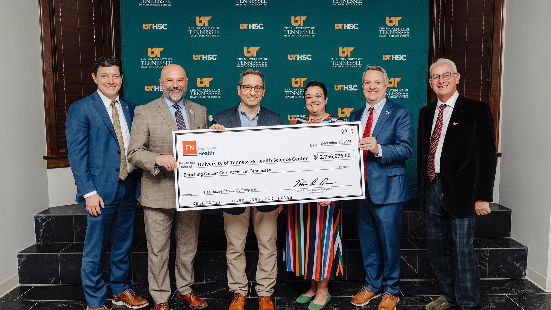 Six people holding up a large ceremonial check.