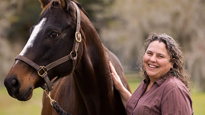 A woman patting a brown horse.