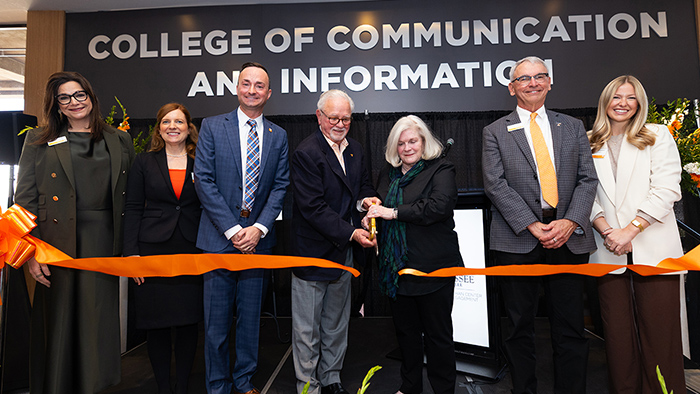 A line of people smiling during a ribbon cutting ceremony.
