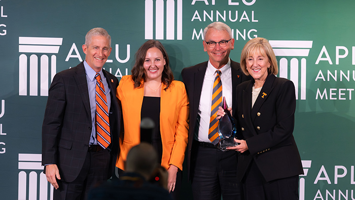 Four people standing together for a photo while holding an award.
