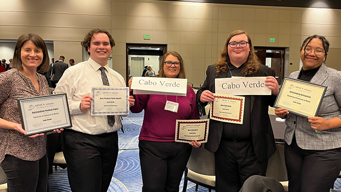 Five people smiling while holding up award certificates.