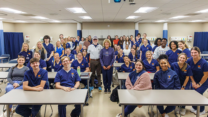 A large group of people in blue scrubs smiling for a group photo.