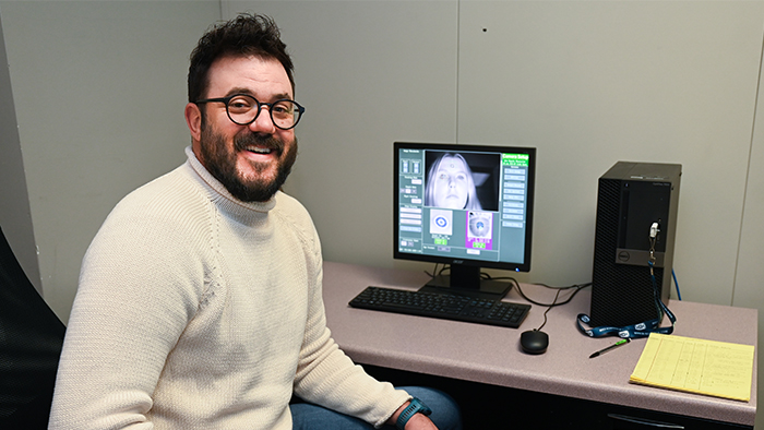 A man posing for a photo next to a computer.