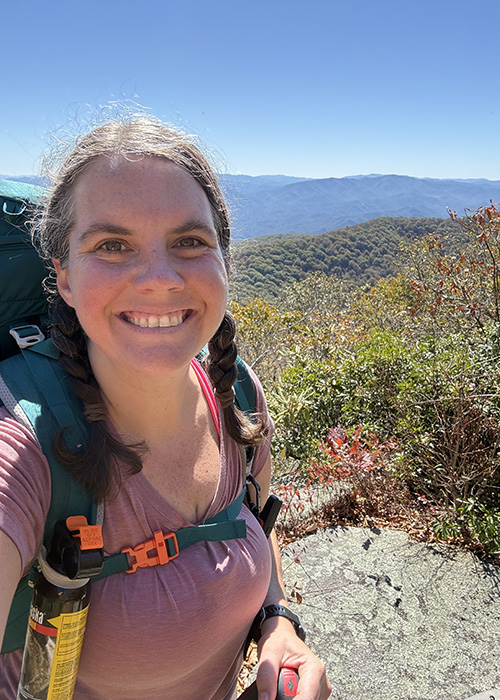 Smiling woman taking a selfie on a mountain top.